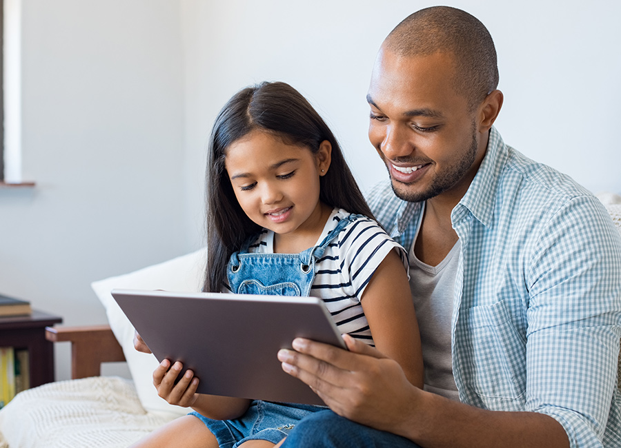 African American man reading off of his iPad with his daughter